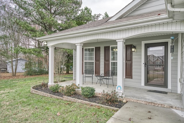 entrance to property featuring a porch, roof with shingles, and a lawn