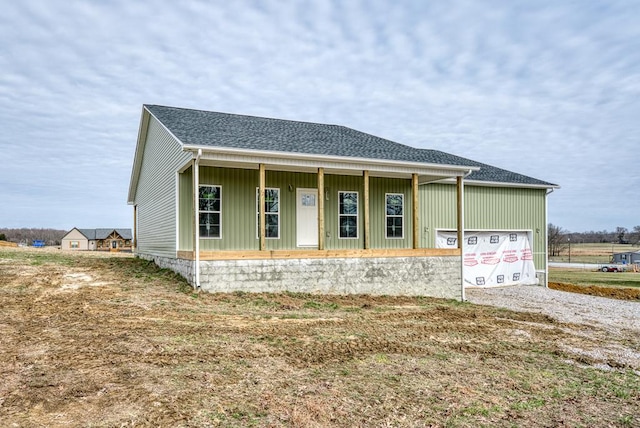 view of front of house featuring a porch, gravel driveway, a shingled roof, and an attached garage