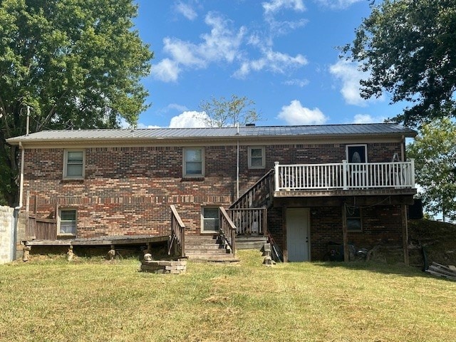 rear view of house with metal roof, brick siding, a yard, and a wooden deck