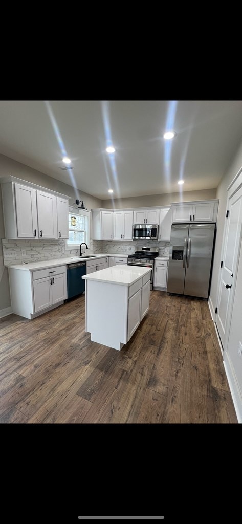 kitchen with a kitchen island, white cabinets, light countertops, appliances with stainless steel finishes, and decorative backsplash