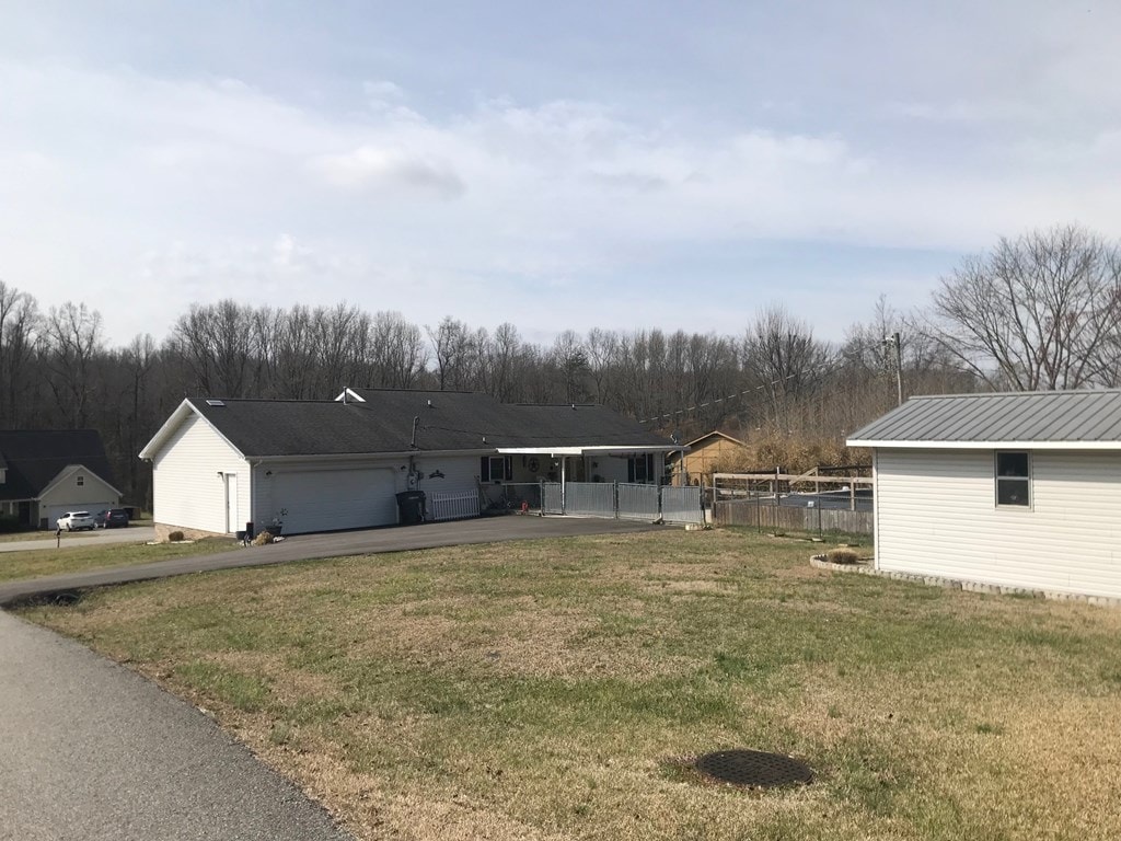 view of front of house featuring a front yard, fence, a garage, and driveway