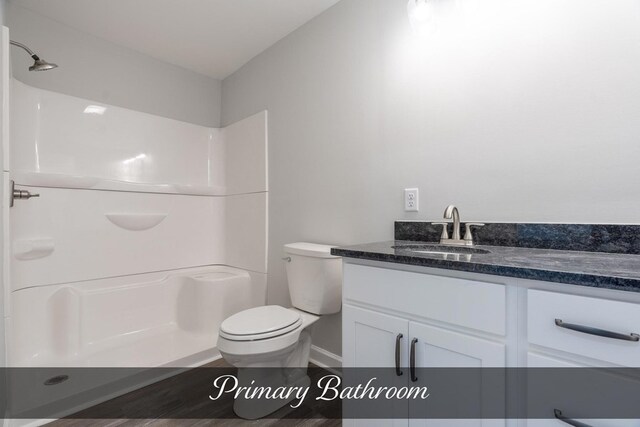 bathroom featuring toilet, walk in shower, wood finished floors, and vanity