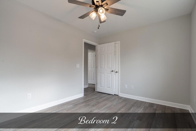 spare room with wood finished floors, a ceiling fan, and baseboards