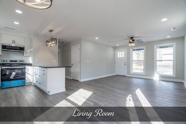 kitchen featuring open floor plan, dark countertops, white cabinetry, and stainless steel range with electric cooktop