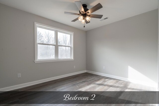 spare room with a ceiling fan, wood finished floors, visible vents, and baseboards