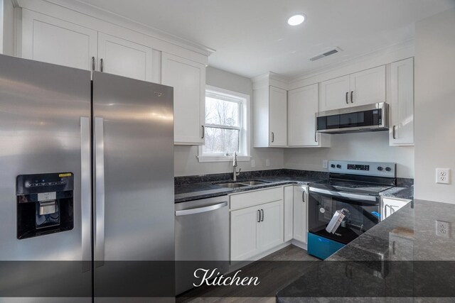 kitchen featuring dark stone countertops, white cabinetry, appliances with stainless steel finishes, and a sink