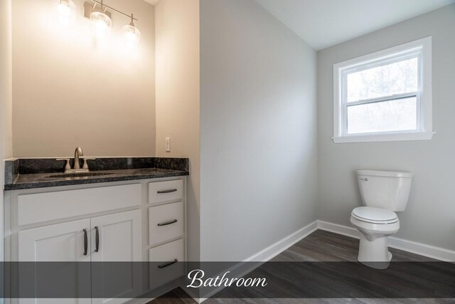 bathroom featuring baseboards, toilet, lofted ceiling, wood finished floors, and vanity