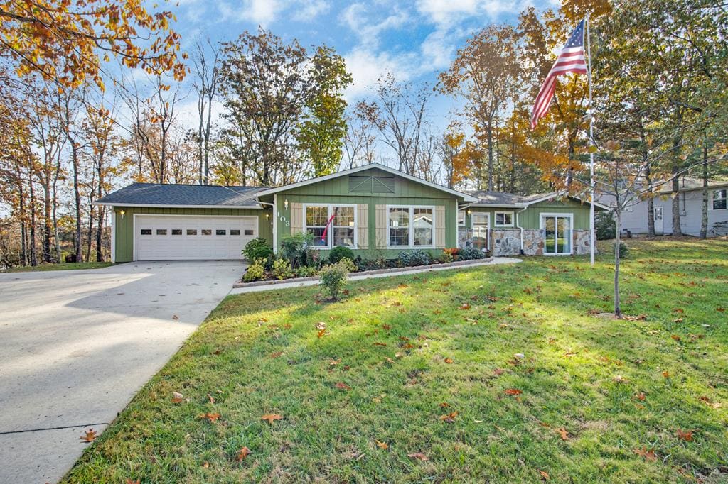 single story home with an attached garage, concrete driveway, and a front yard