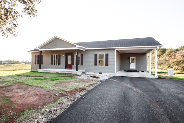 ranch-style home with an attached carport, aphalt driveway, covered porch, roof with shingles, and crawl space