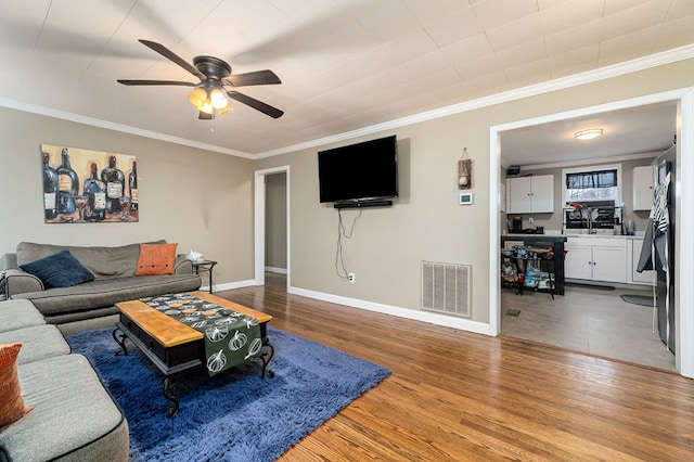 living room with ornamental molding, visible vents, and wood finished floors