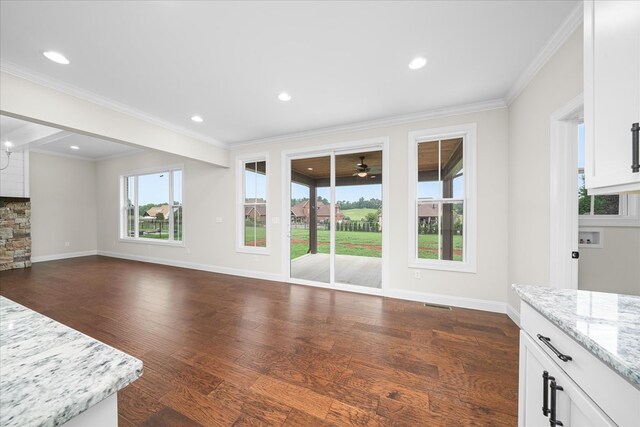 unfurnished living room featuring ornamental molding, dark wood-type flooring, and baseboards