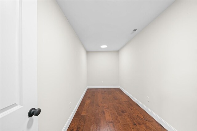 corridor with baseboards and wood finished floors