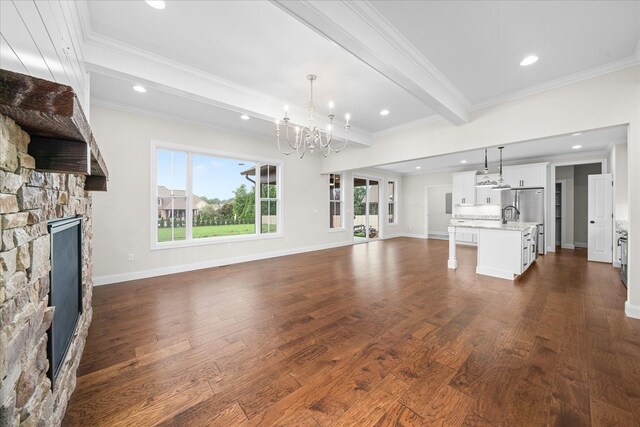 unfurnished living room featuring baseboards, dark wood finished floors, a stone fireplace, and beamed ceiling