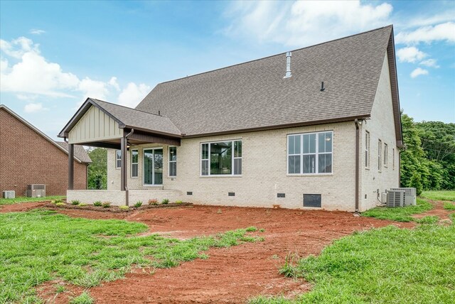 rear view of property featuring cooling unit, a shingled roof, brick siding, a yard, and crawl space