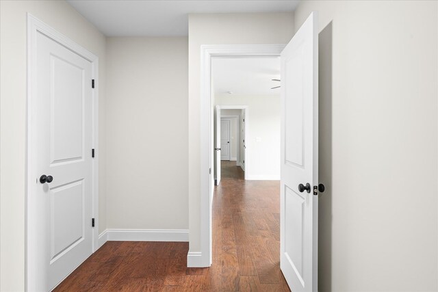 hallway featuring dark wood-style flooring and baseboards