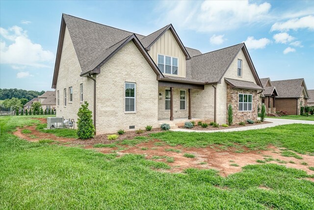 view of front of house with brick siding, a shingled roof, board and batten siding, a front yard, and crawl space