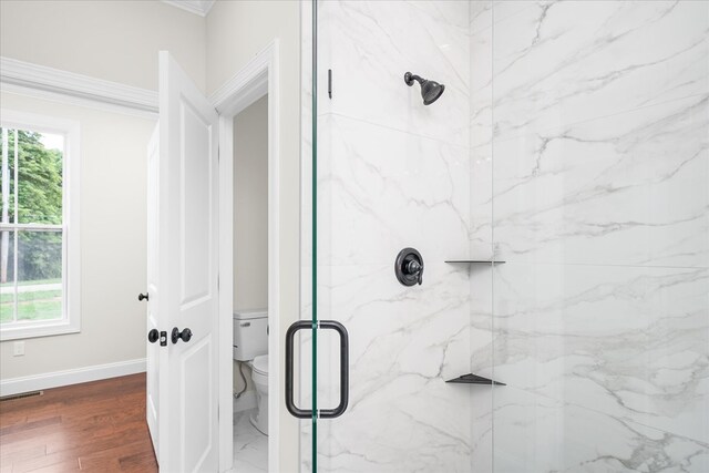 full bathroom featuring toilet, wood finished floors, visible vents, baseboards, and a marble finish shower