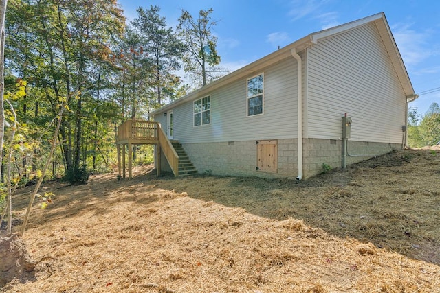 view of side of home with a deck, crawl space, a yard, and stairway