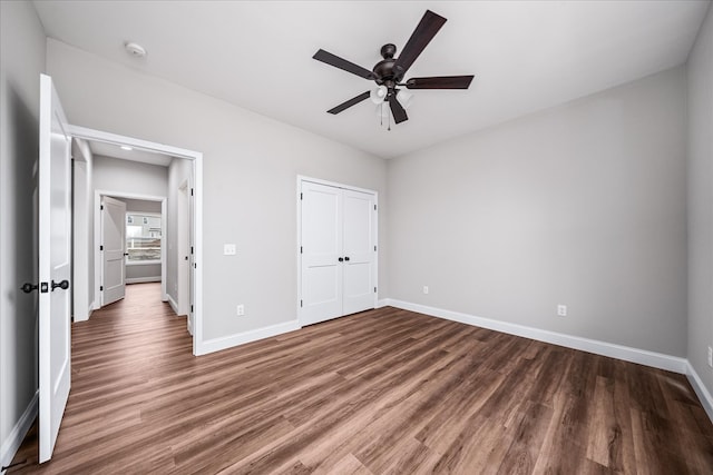 unfurnished bedroom featuring a closet, a ceiling fan, baseboards, and wood finished floors