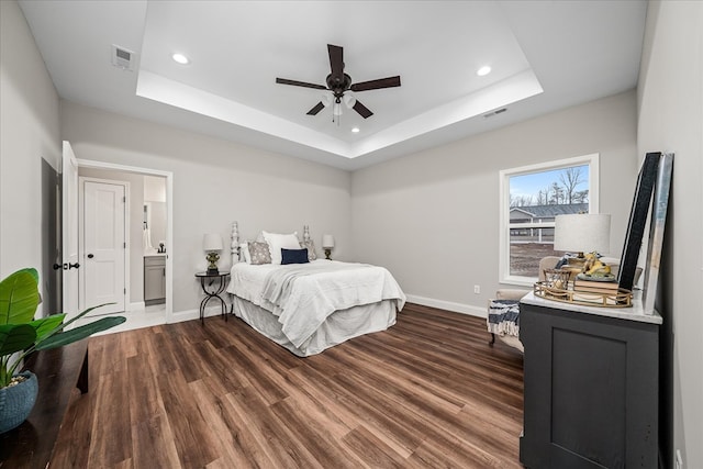 bedroom with visible vents, a raised ceiling, and wood finished floors