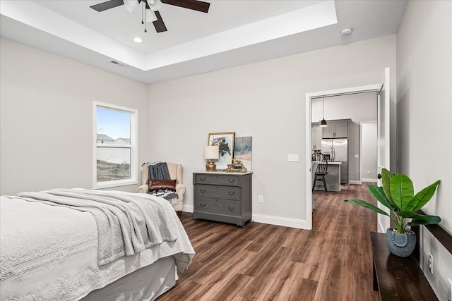 bedroom with baseboards, a tray ceiling, recessed lighting, dark wood-style flooring, and stainless steel fridge