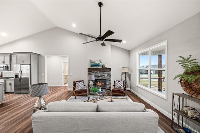 living room with dark wood finished floors, a stone fireplace, a ceiling fan, and baseboards