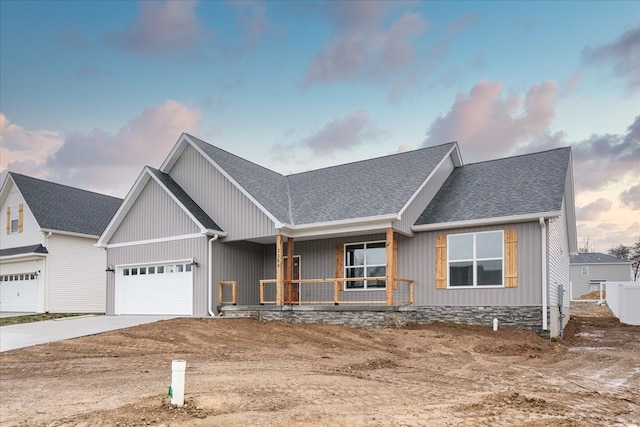 view of front of house with covered porch, driveway, an attached garage, and roof with shingles