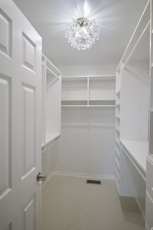 spacious closet with carpet, visible vents, and a chandelier