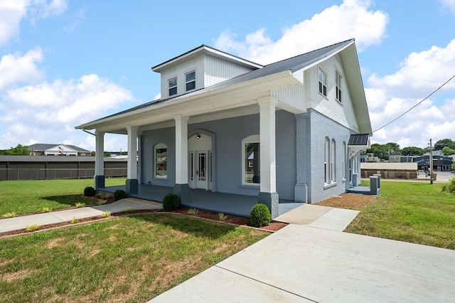 view of front of house featuring covered porch, a front yard, fence, and brick siding