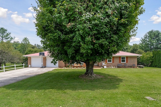 view of front of property featuring brick siding, concrete driveway, a front yard, fence, and metal roof