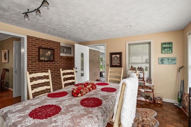 dining space with brick wall, baseboards, and a textured ceiling