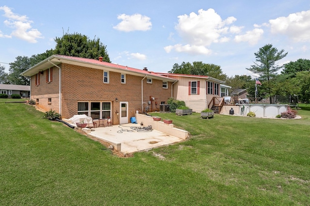 back of house with a patio area, an outdoor pool, a lawn, and brick siding