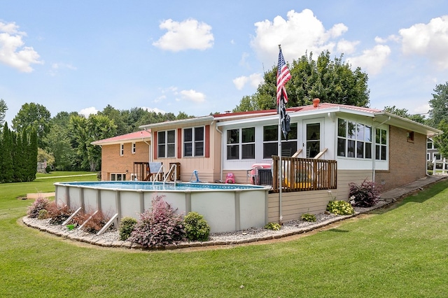 rear view of property featuring brick siding, a lawn, and an outdoor pool