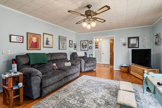 living room featuring ceiling fan, baseboards, wood finished floors, and crown molding