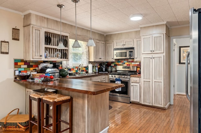 kitchen featuring a breakfast bar, pendant lighting, appliances with stainless steel finishes, butcher block countertops, and a peninsula