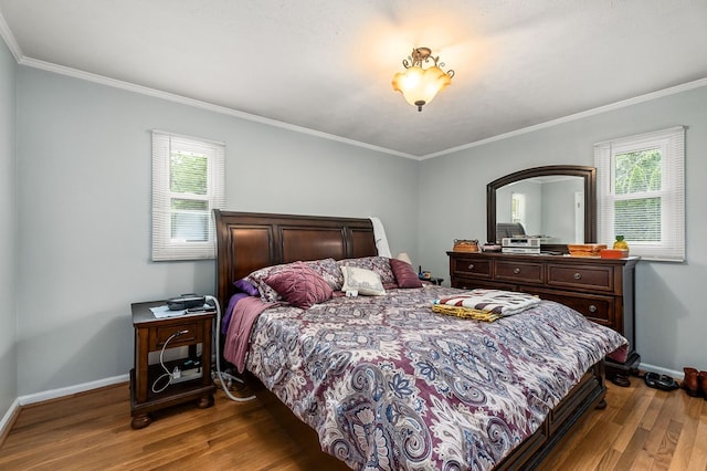 bedroom with ornamental molding, multiple windows, wood finished floors, and baseboards