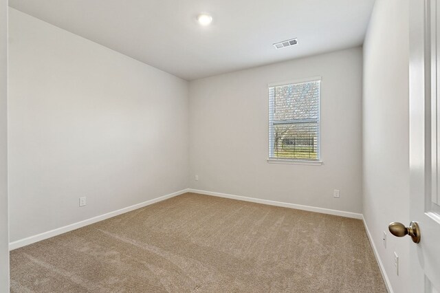 spare room featuring carpet flooring, visible vents, and baseboards