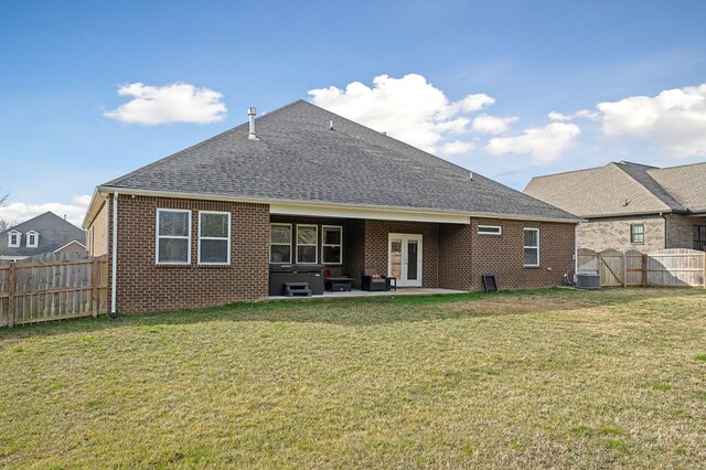 rear view of house with a shingled roof, a fenced backyard, a patio area, central AC, and brick siding