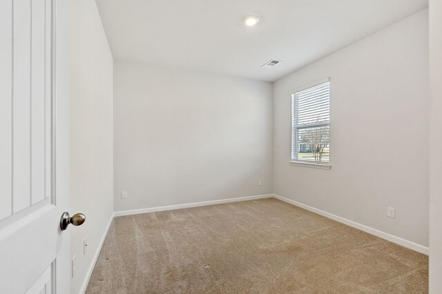 empty room featuring light carpet, visible vents, and baseboards