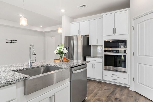 kitchen with white cabinets, visible vents, stainless steel appliances, and decorative light fixtures