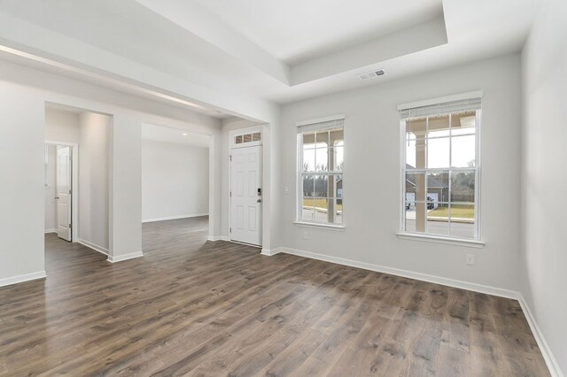 entrance foyer with a tray ceiling, visible vents, dark wood finished floors, and baseboards