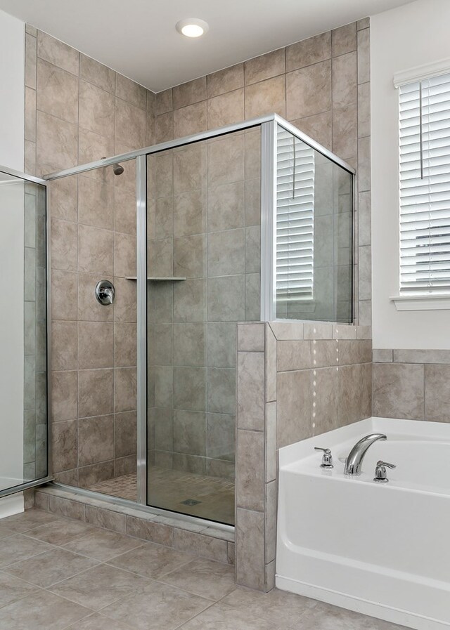 bathroom featuring a shower stall, a bath, and tile patterned floors