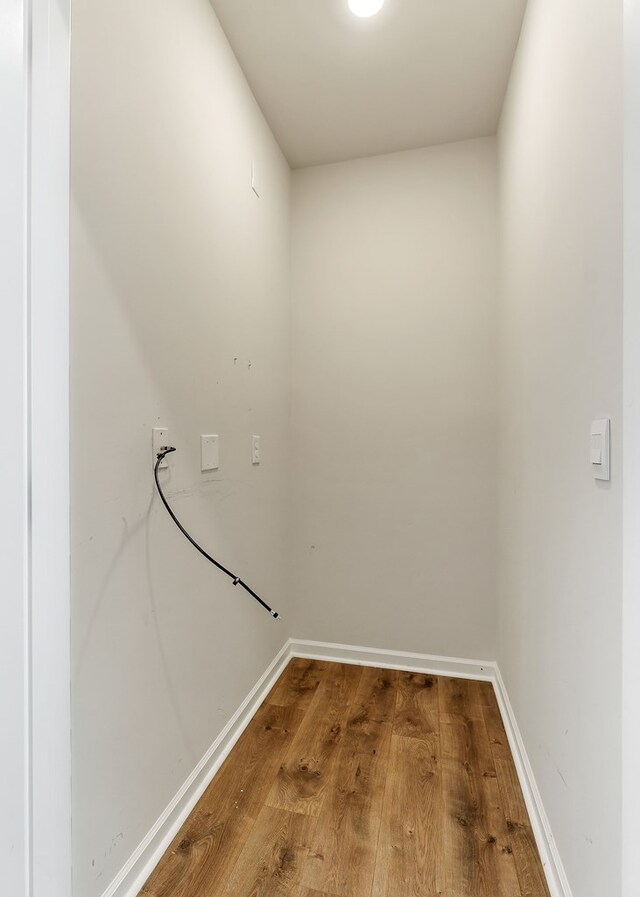 laundry area with baseboards and wood finished floors