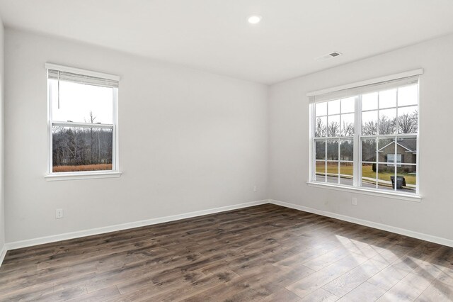 unfurnished room featuring visible vents, baseboards, and dark wood finished floors