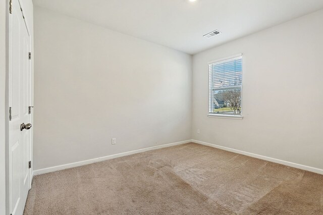 unfurnished room with light carpet, visible vents, and baseboards