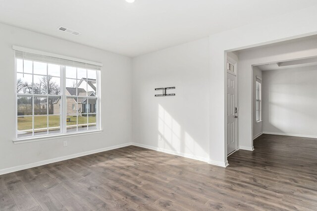 empty room featuring dark wood finished floors, visible vents, and baseboards