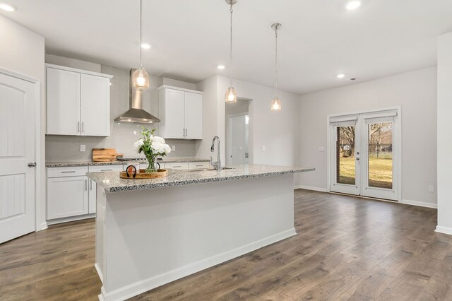 kitchen featuring a center island with sink, pendant lighting, and white cabinets