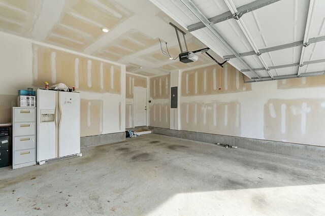 garage featuring electric panel, white fridge with ice dispenser, and a garage door opener