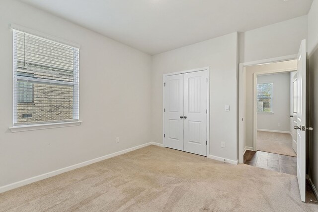 unfurnished bedroom featuring light carpet, baseboards, and a closet