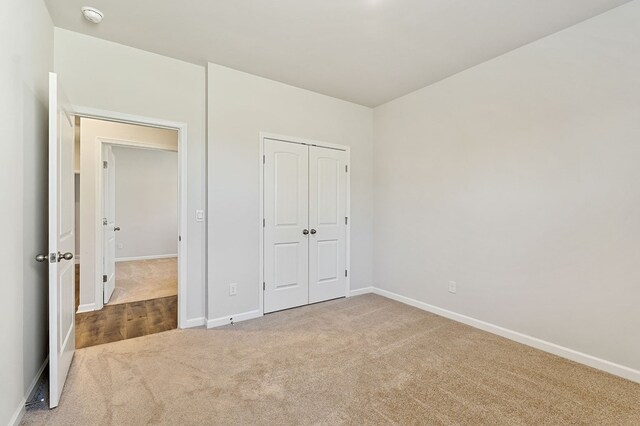 unfurnished bedroom with a closet, carpet flooring, and baseboards